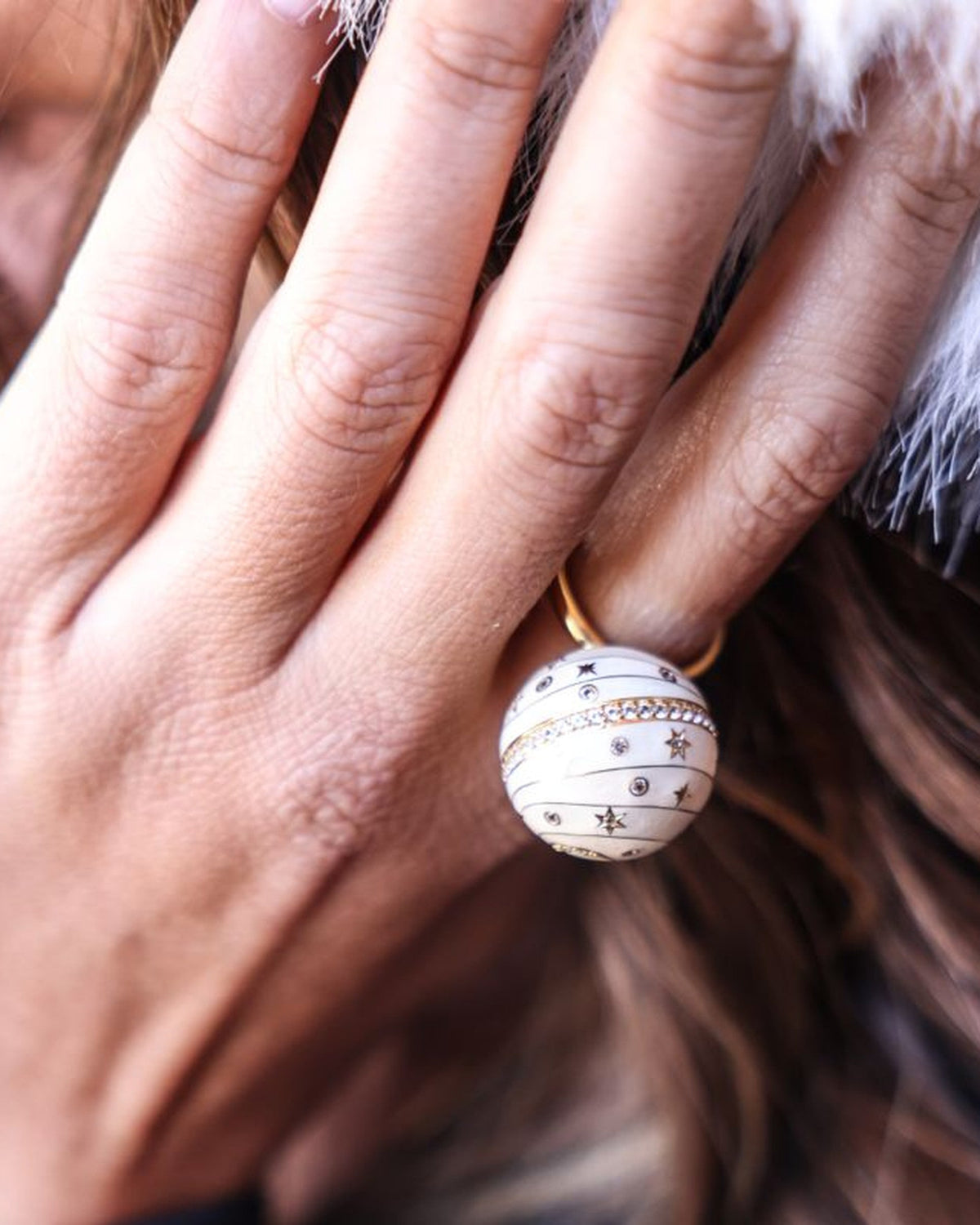 Bubble Circle I worn on the hand — 18k gold sphere ring with ivory grand feu enamel, engraved stars and a pavé diamond band, by Sandrine Barabinot